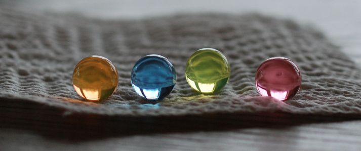 Four translucent orbs of different colors on a white paper towel with light shining through.